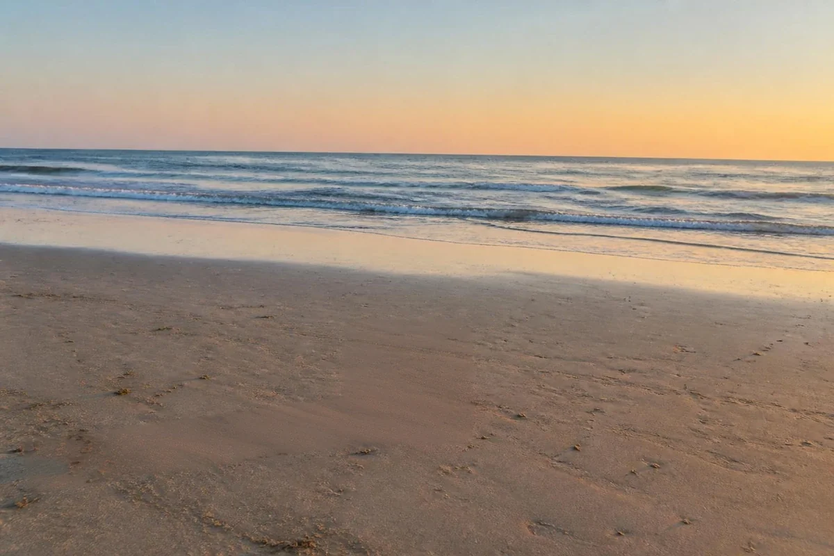 The same beach at sunset with the red bucket removed by AI